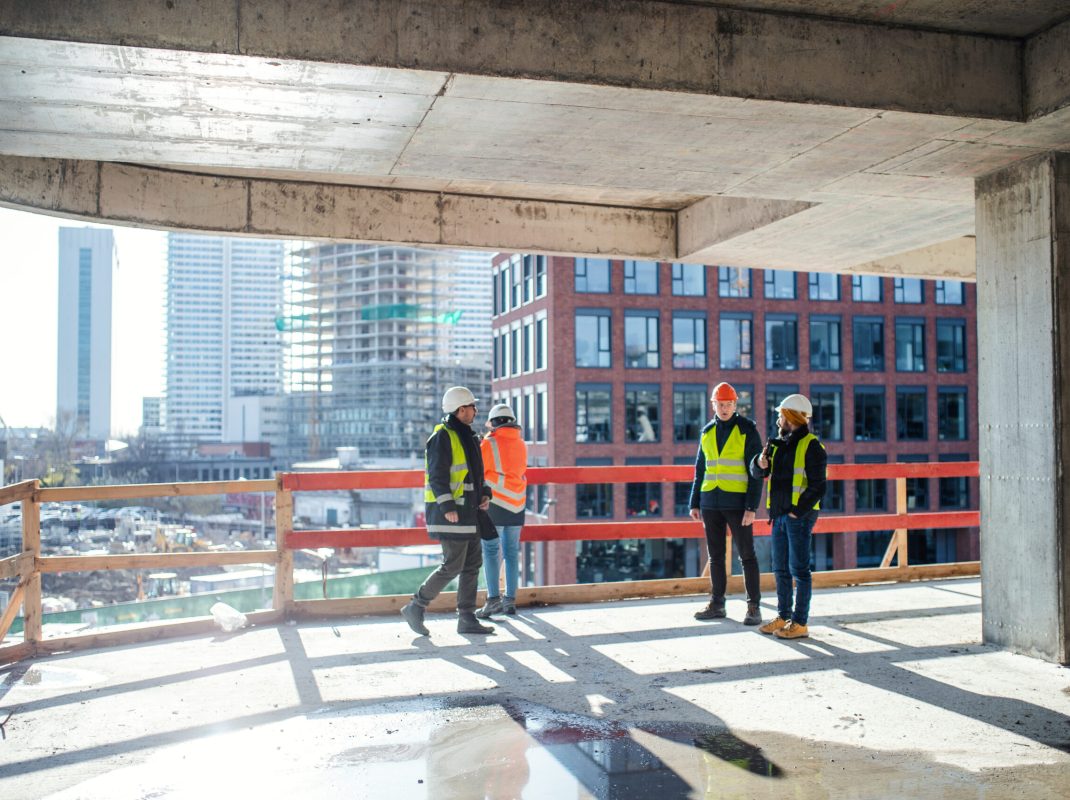 A group of engineers standing on construction site, talking.